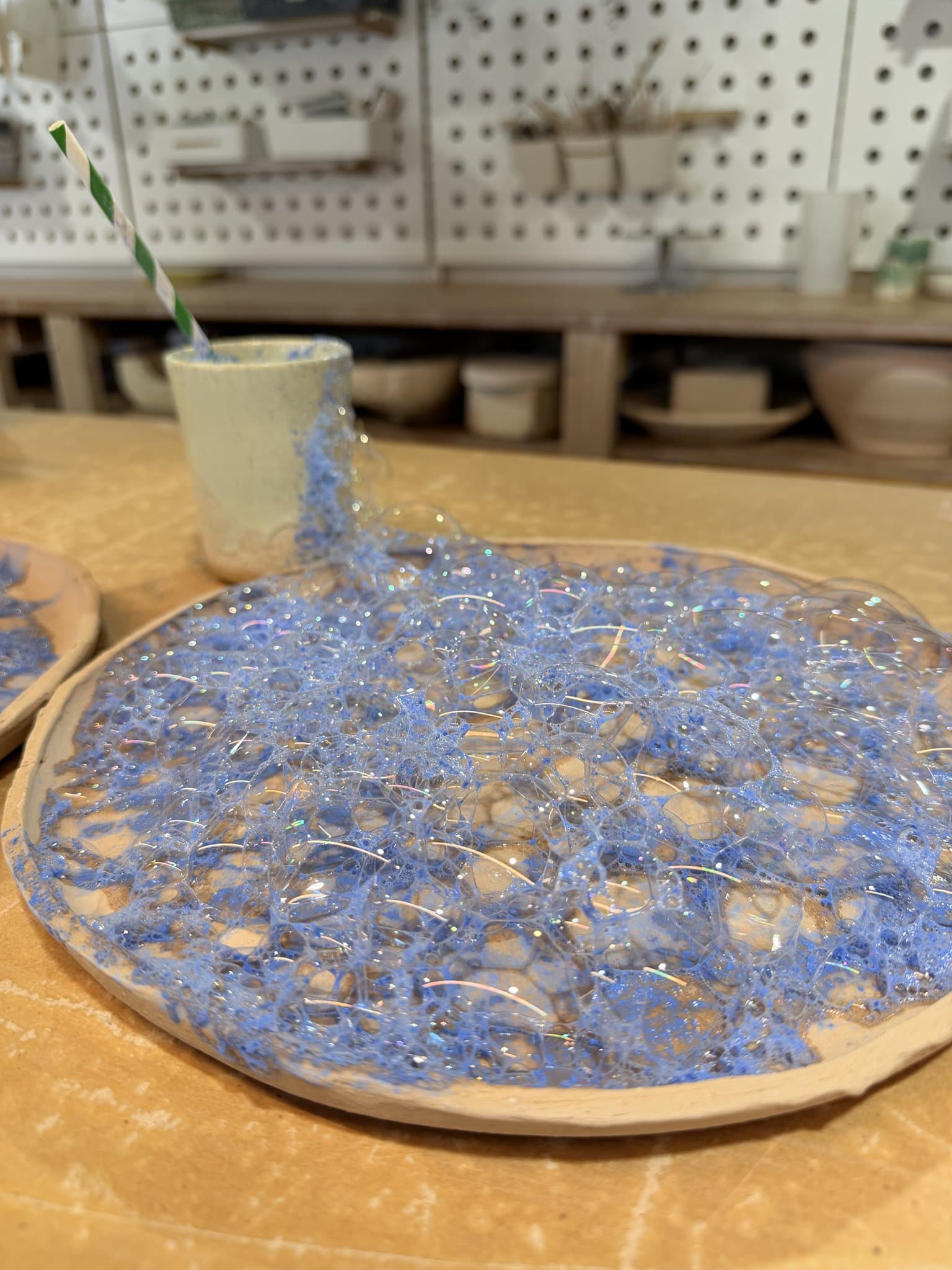 A handmade plate part-way through, its blue crawl glaze still bubbling on the surface.