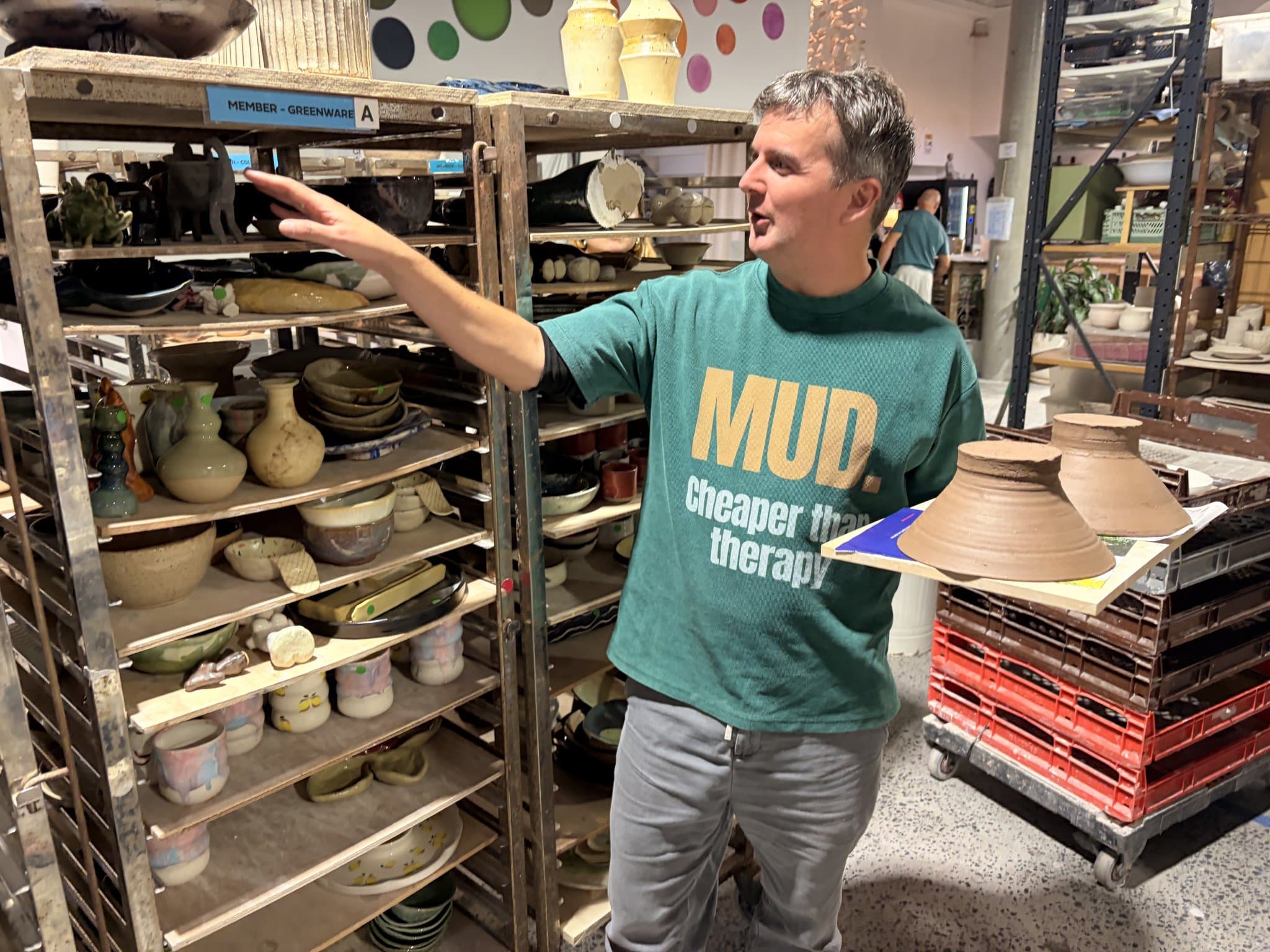 A studio rack of members' greenware, each piece logged and accounted for.