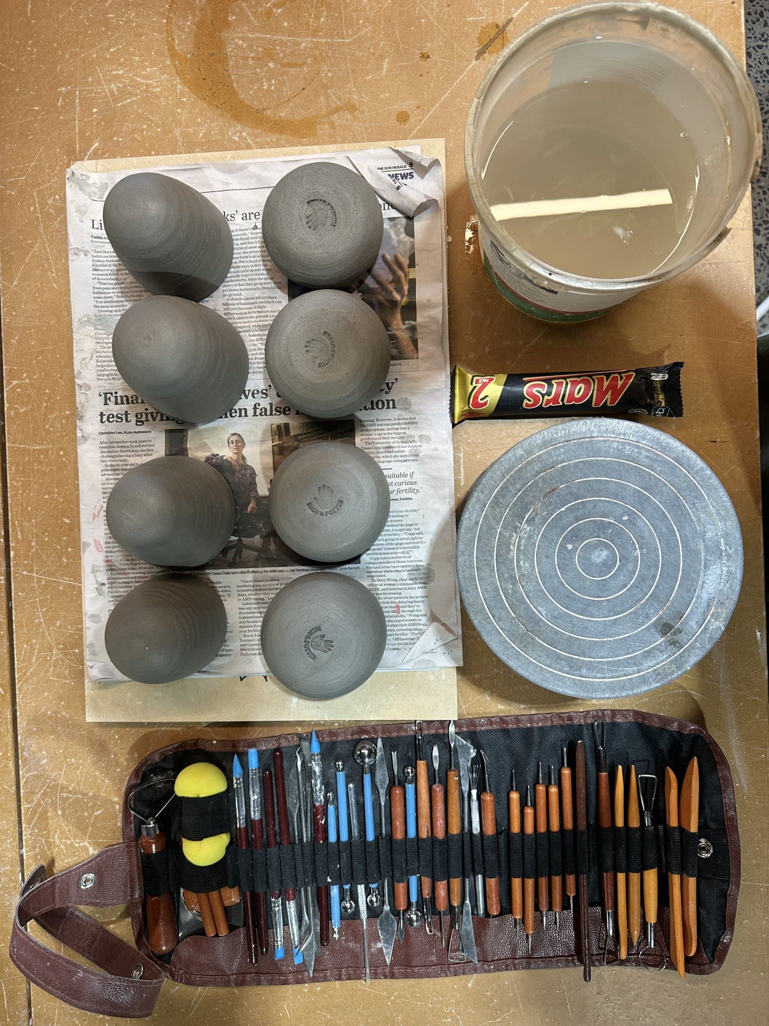 Pottery tools and greenware laid out on a studio bench.