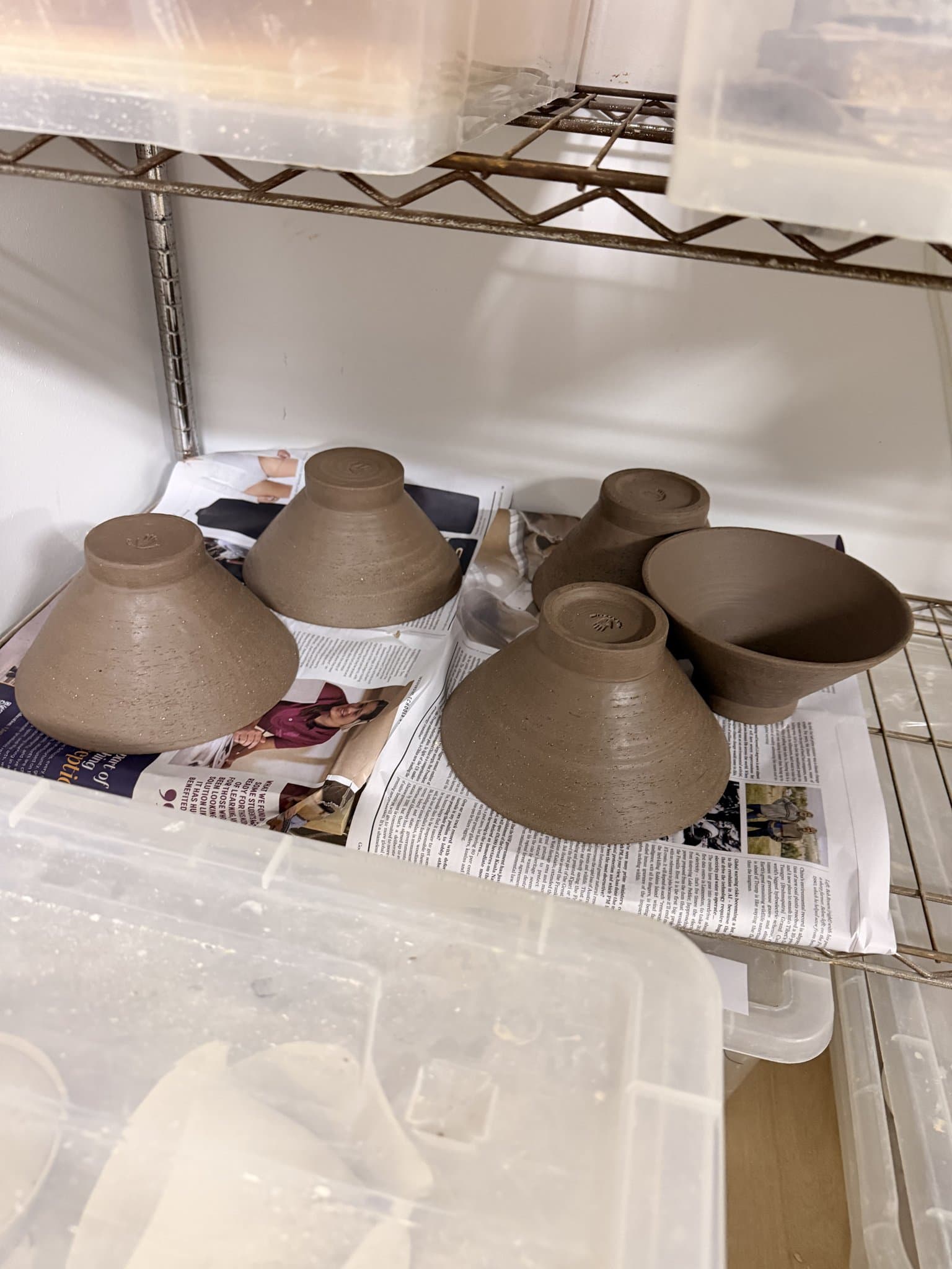 Rows of class greenware drying on studio shelves.